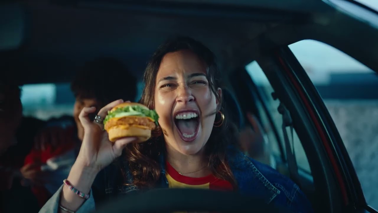 Fotograma real de la campana Pizza King de Burger King Francia para el Mundial 2026: aficionada celebra en un coche comiendo una hamburguesa