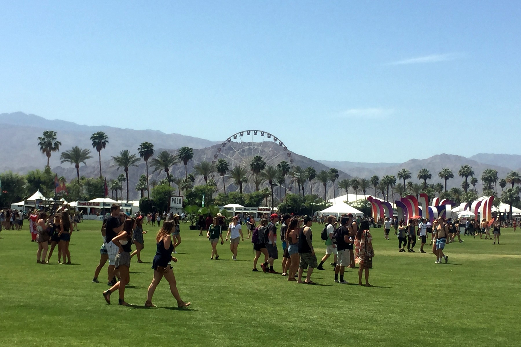 Asistentes de Coachella en el recinto del festival con la noria y las palmeras al fondo