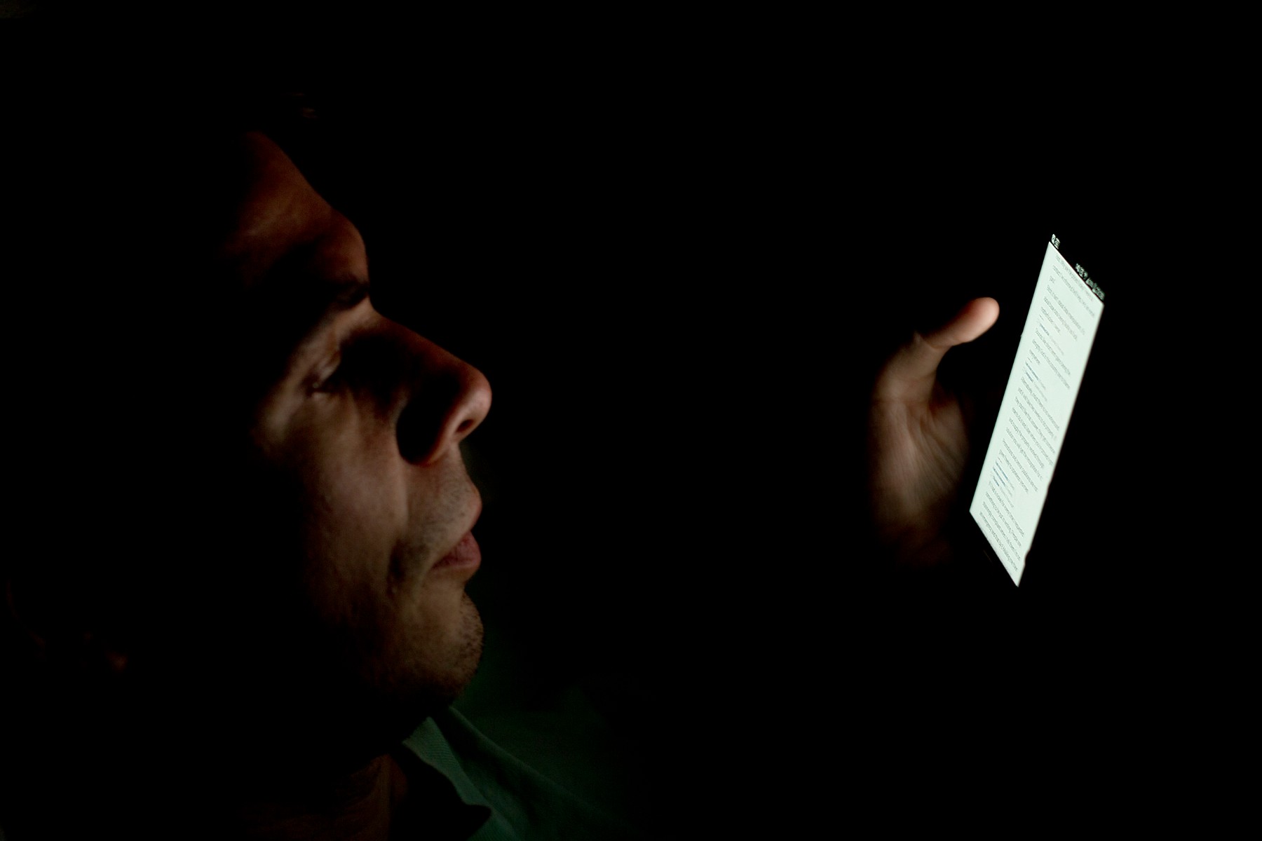 Persona mirando la pantalla iluminada de su móvil a oscuras, como se consumen los microdramas