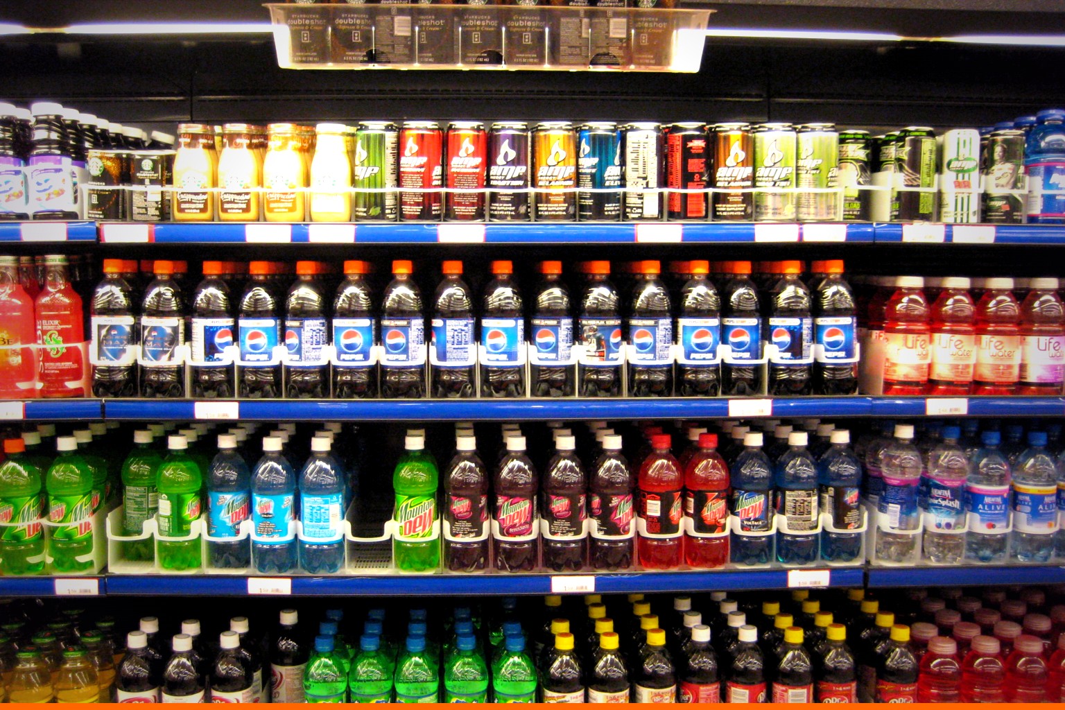 Estantería de supermercado con filas alineadas de botellas de Pepsi y Mountain Dew, marcas de PepsiCo