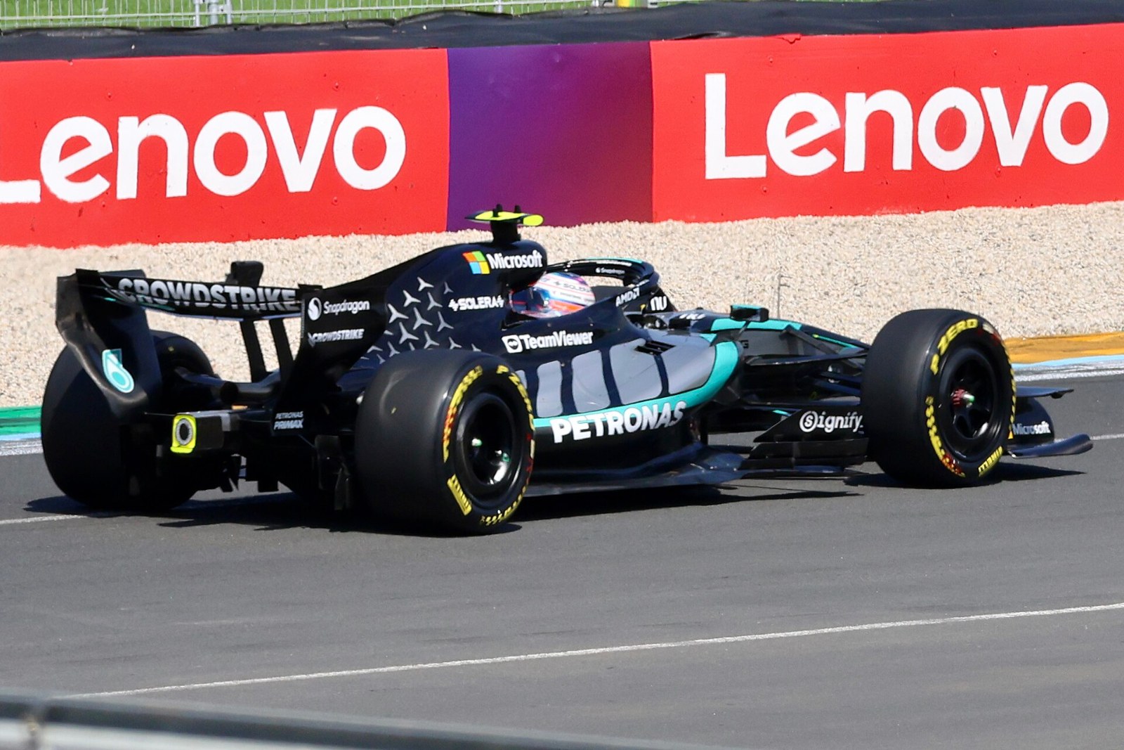 Monoplaza Mercedes de Formula 1 de Kimi Antonelli en pista con vallas publicitarias de patrocinadores al fondo