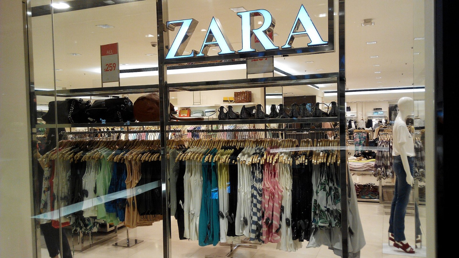 Interior de una tienda de Zara con el logotipo de la marca y percheros llenos de ropa