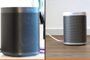 Dos altavoces Sonos en dos habitaciones distintas, un Sonos One sobre un escritorio y un Play:1 en el suelo, ilustrando la idea de sistema de sonido para toda la casa