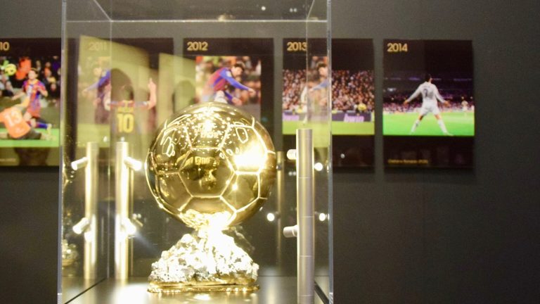 Trofeo del Balón de Oro en una vitrina, con fotos de ganadores anteriores al fondo