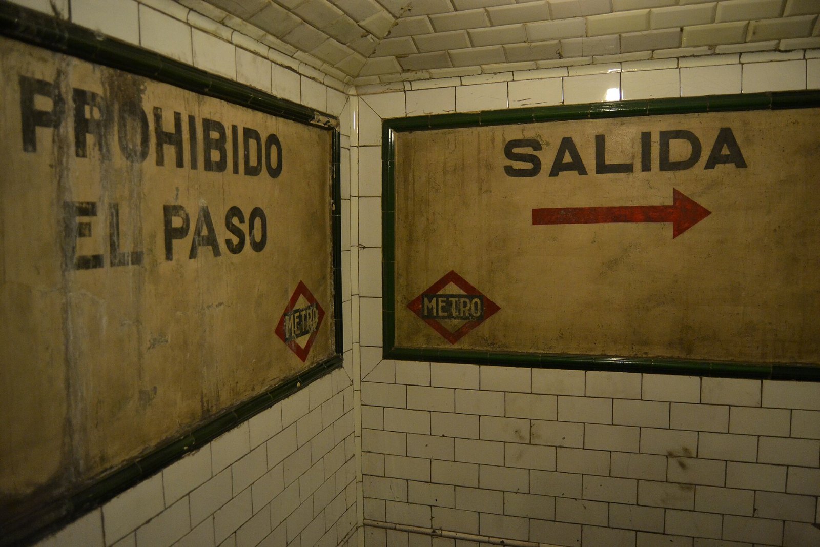 Carteles de azulejo «Salida» y «Prohibido el paso» en un pasillo de la estación de Chamberí
