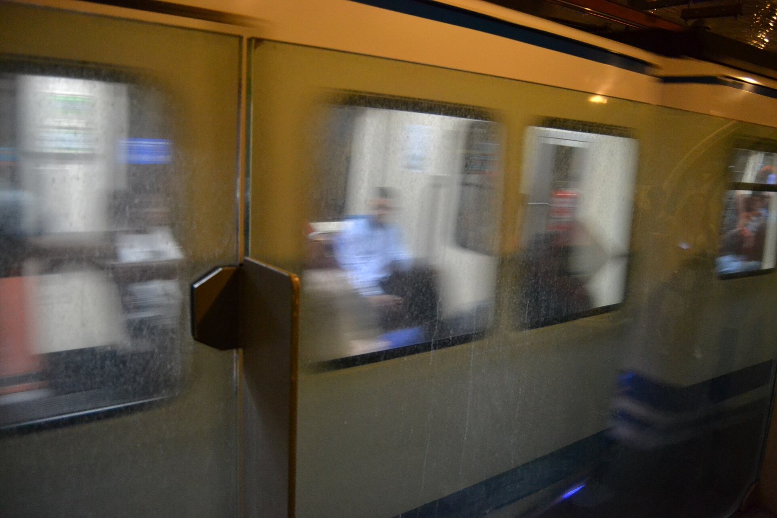 Tren de la Línea 1 del Metro de Madrid pasando por la estación de Chamberí sin detenerse, visto tras el cristal del andén