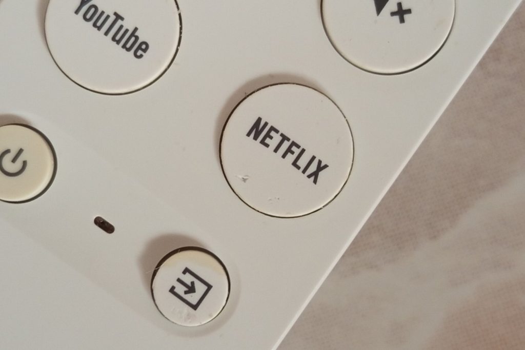 Mando de un Chromecast con Google TV con el botón de YouTube junto al de Netflix