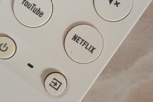 Mando de un Chromecast con Google TV con el botón de YouTube junto al de Netflix