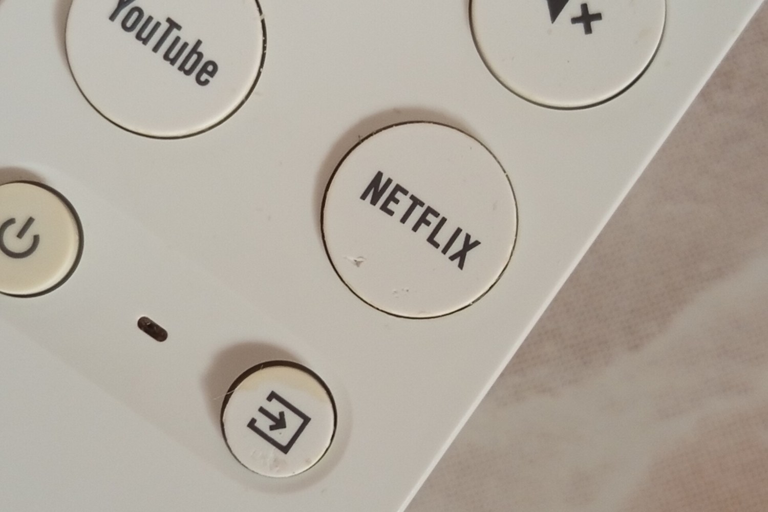Mando de un Chromecast con Google TV con el botón de YouTube junto al de Netflix