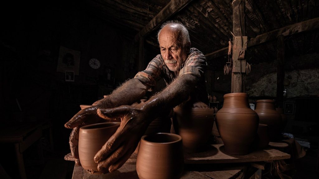 Manos de un alfarero modelando vasijas de barro en su taller, imagen sobre la nueva política de IA de Etsy