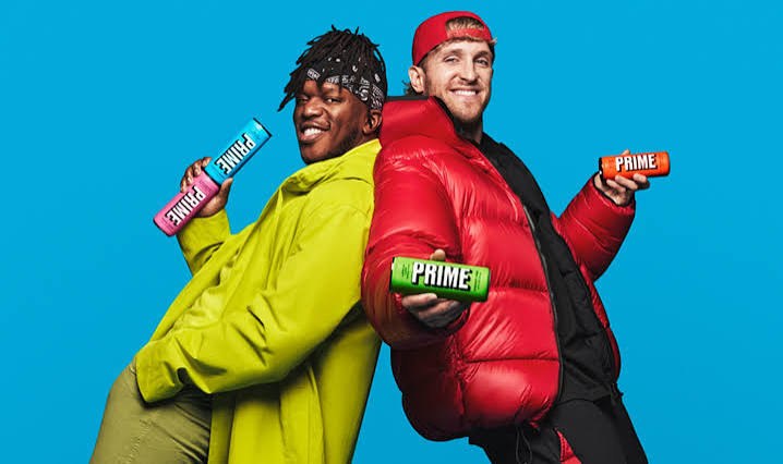 KSI y Logan Paul, espalda con espalda sobre fondo azul, con latas de Prime en las manos.