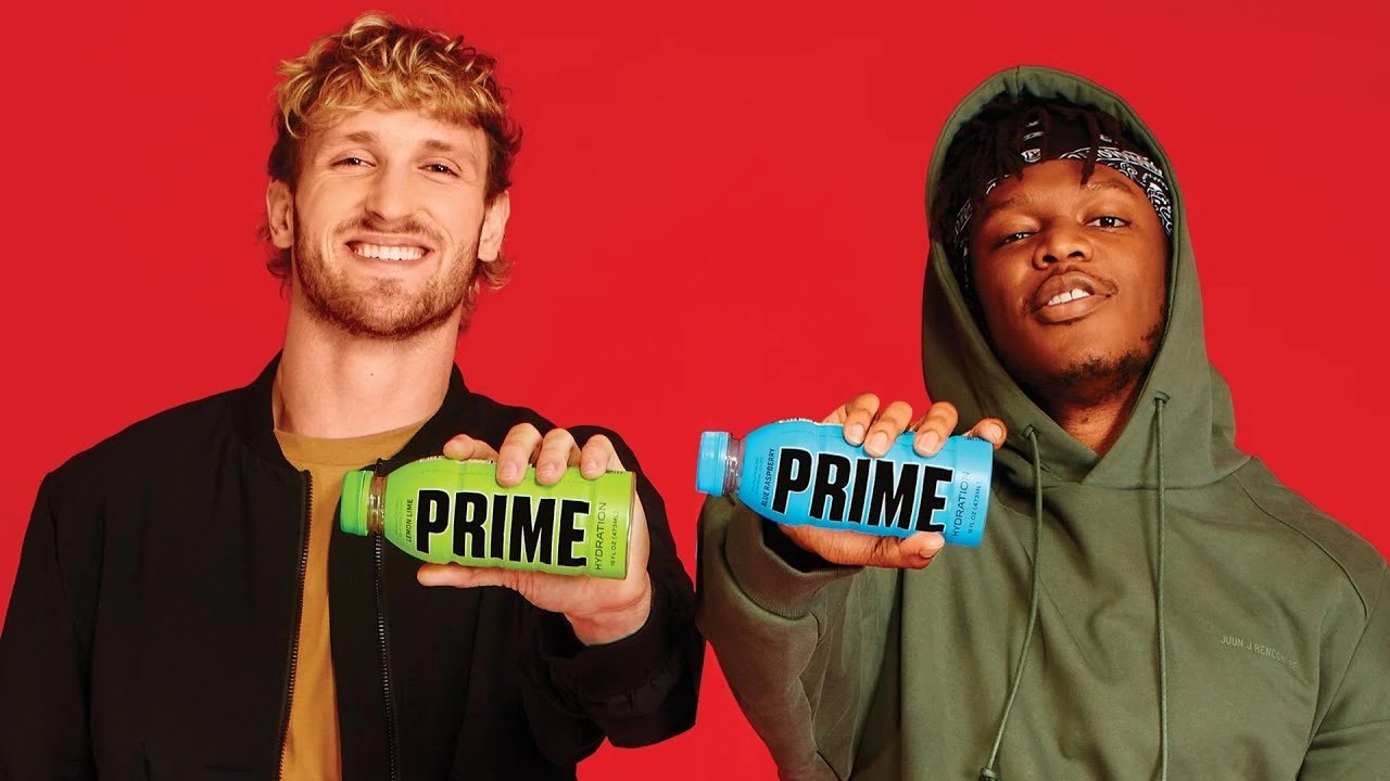 Logan Paul y KSI sonríen sobre fondo rojo, cada uno con una botella de Prime Hydration en la mano.