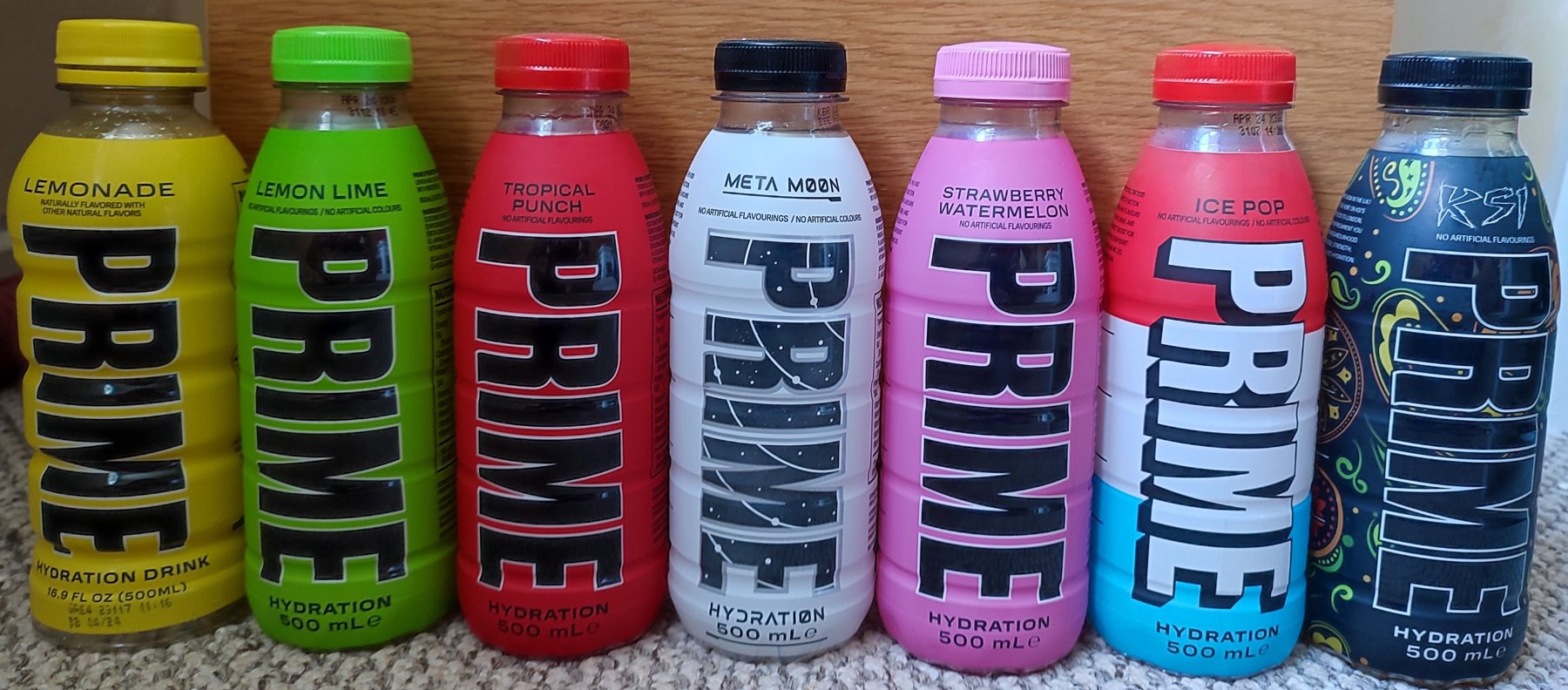 Siete botellas de Prime Hydration de distintos sabores alineadas sobre una mesa.