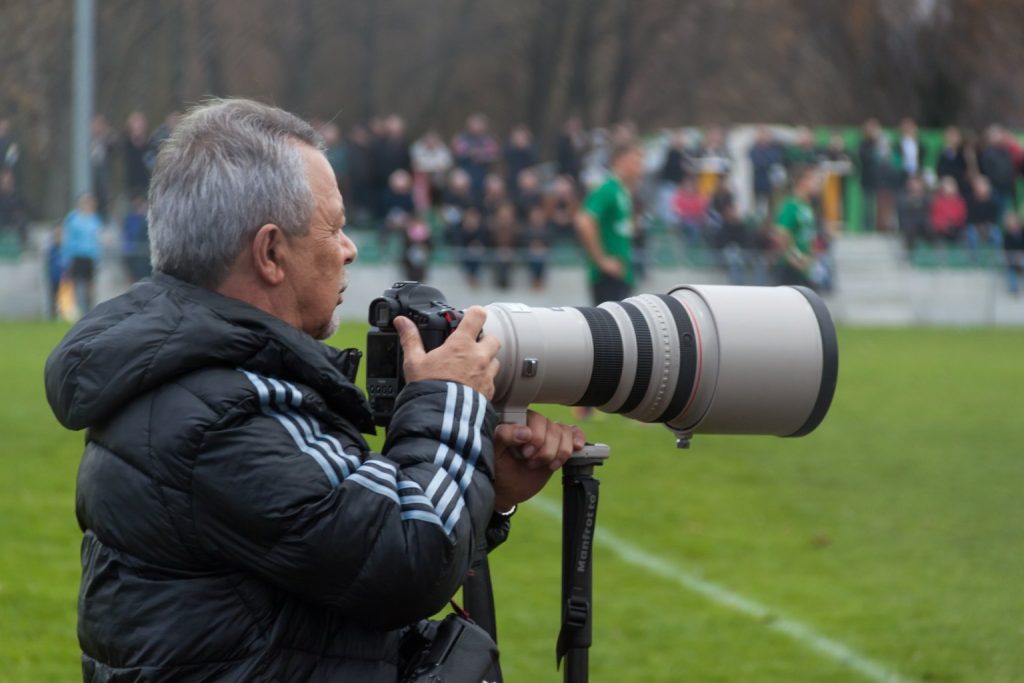 Fotógrafo profesional con teleobjetivo cubriendo un partido de fútbol, el tipo de imagen editorial que la IA generativa no puede sustituir